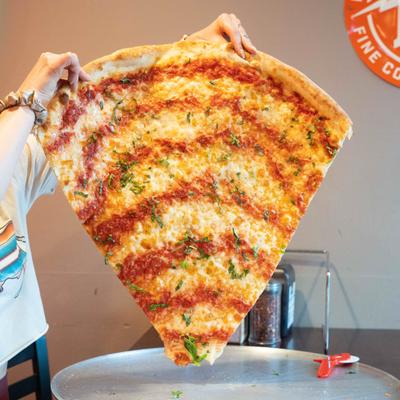 Classic New York–style pizza slice being held up.