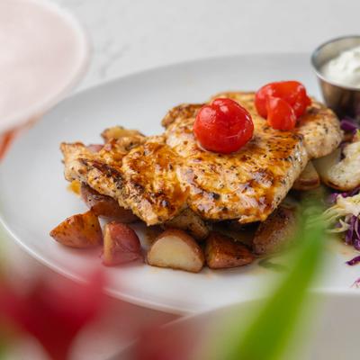 Grilled chicken in sauce, with red potatoes, citrus slaw, and tomatoes.