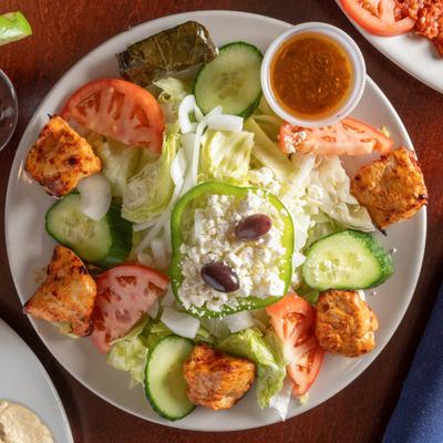 Mediterranean grilled chicken salad with feta cheese, cucumbers, tomatoes, olives, and dressing.