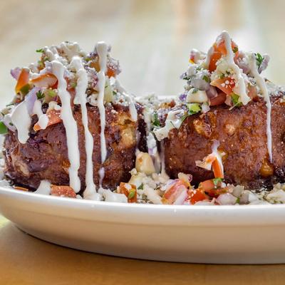 Tamales cakes topped with a drizzle of white crema, pico de gallo, and cotija cheese.