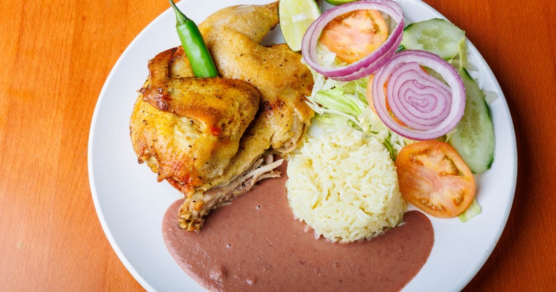Half of chicken served with rice, beans and salad