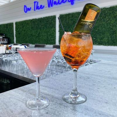 Cocktail in a martini glass, alongside Aperol Spritz with small bottle of prosecco inserted.