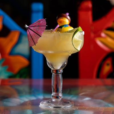 Margarita cocktail garnished with a pink cocktail umbrella and small rubber duck.