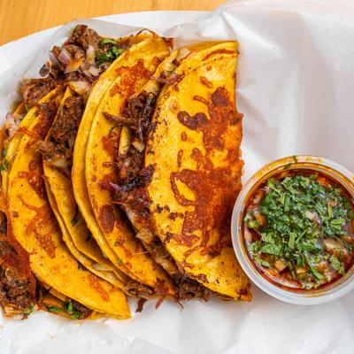 Birria tacos served with consommé.