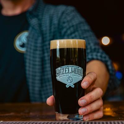 A hand holding a glass of dark beer.