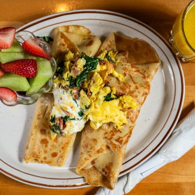Crepes topped with scrambled eggs and fruit.