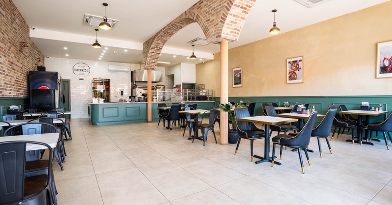 Spacious café with exposed brick arches, teal countertops, and black chairs