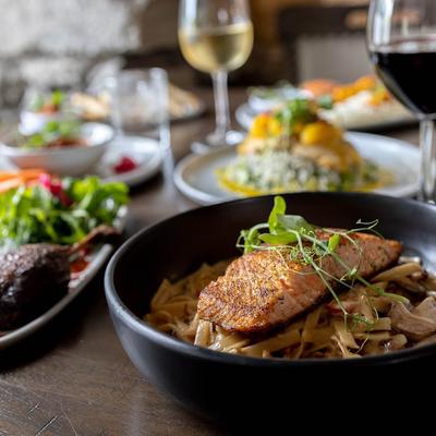 Salmon pasta plate displayed with other dishes and drinks, close up.