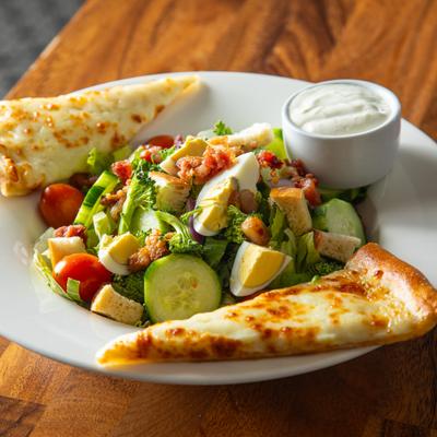 Traditional House Salad with fresh vegetables, hard-boiled egg, dressing and cheesy bread on the side.