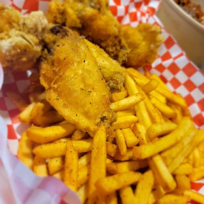 Fried chicken tenders served with fries on checkered paper.