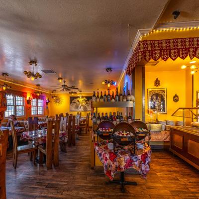 Interior with booth and table seating, traditional Indian artwork and a buffet setup.