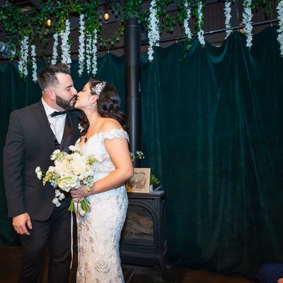 A bride and groom exchange a kiss in a room with wedding decorations