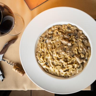 Fettuccine Ai Porcini served with a glass of red wine.