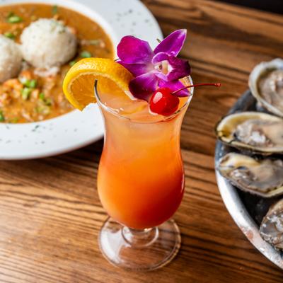 Tropical cocktail with orange, cherry, and orchid garnish.