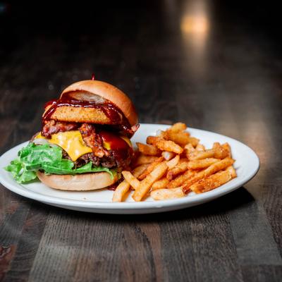 Bacon cheeseburger with lettuce, onion ring, and fries.