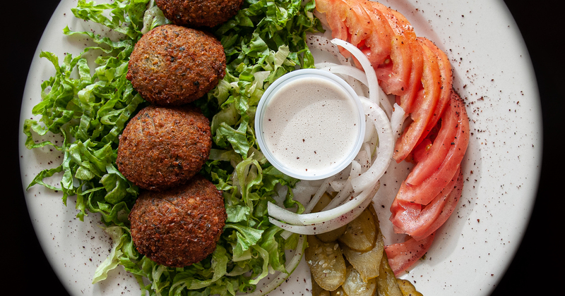 Meatballs, green, tomato and cucumber salad, white dip in the middle