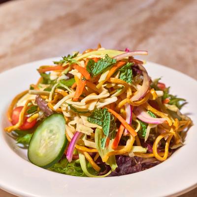 Salad with carrots, cabbage, spring mix, onion, tomatoes, cucumber, mango, and crispy noodles.