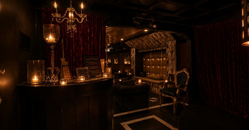 Interior with black tufted couches, a gold bench, and red velvet curtains