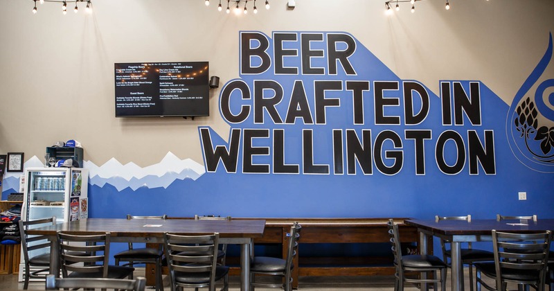 Tables and seating by a wall with a mural writing, reading Beer Crafted in Wellington