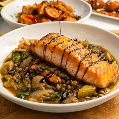 Salmon Con Lenticchie being drizzled with balsamic glaze.