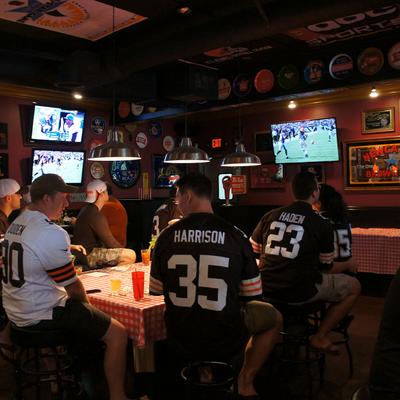 Guys in jerseys hanging out, drinking and watching the game