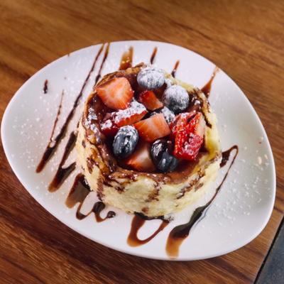 San Sebastian Cheesecake garnished with mixed berries and a chocolate drizzle.