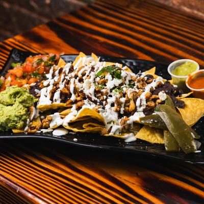 Loaded Nachos plate with sides of  salsa, guacamole, pico de gallo.