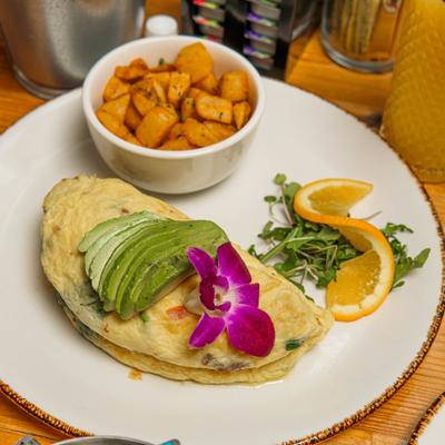 Avocado Omelette served with home fries and various garnishes.