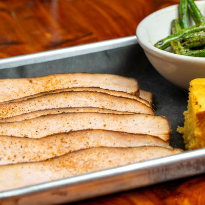 Smoked turkey breast entree with a side of green beans and corn bread.