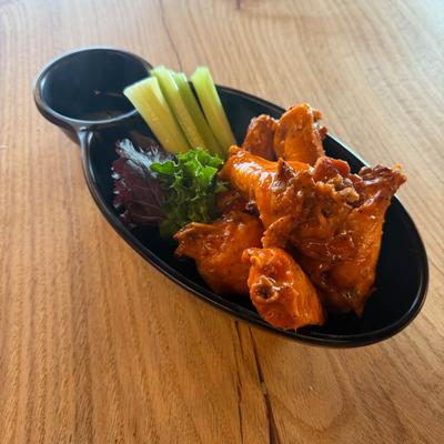 Buffalo chicken wings served with celery sticks and dipping sauce.