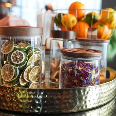 Glass jars holding dehydrated lime wheels and dried edible flower petals.