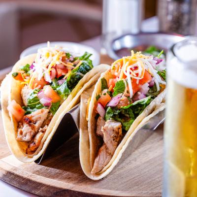 Grilled chicken tacos topped with tomatoes and grated cheese, paired with draft beer.
