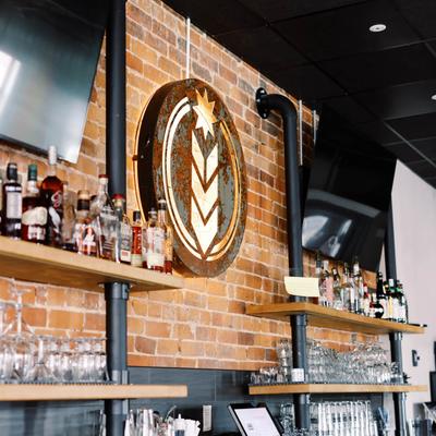 Bar area with liquor bottles, glassware, brick wall, and metal sign.