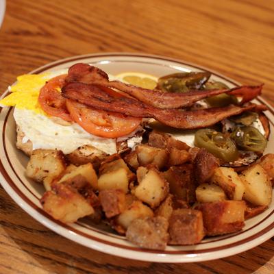 Bagel with bacon, fried egg, tomato, jalapenos, cream cheese, and potatoes.