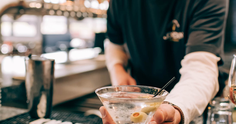 Bartender serving a cocktail behind counter