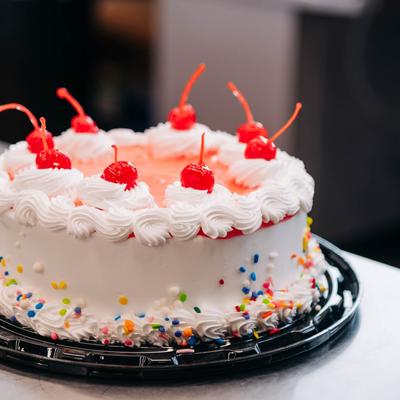 A round cake topped with white frosting and bright red cherries.