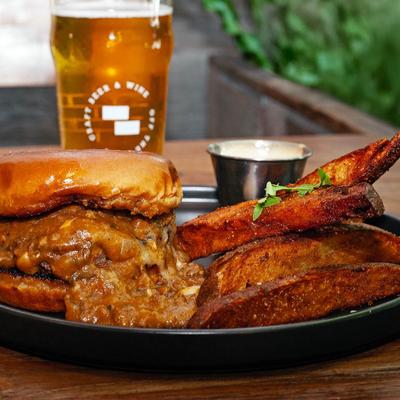 Chili cheese burger served with fries, dipping sauce, and beer.
