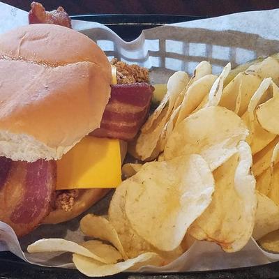 Bacon cheeseburger served with potato chips, close-up.