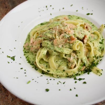 Fettuccine pasta with salmon in a creamy green herb sauce.