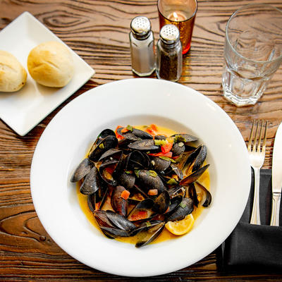 Clams in sauce dish with bread and salt and pepper shakers