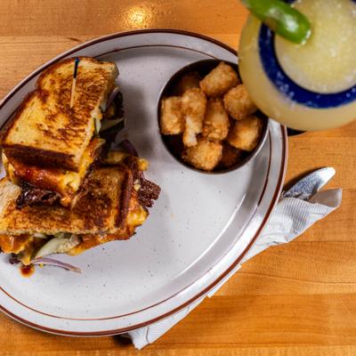 Grilled sandwich served with tater tots and margarita cocktail.