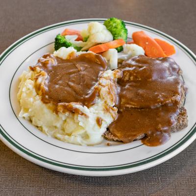 Meatloaf, mashed potatoes with brown gravy and vegetables.