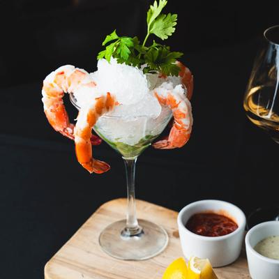 Jumbo shrimp cocktail served with cocktail sauce and wine.