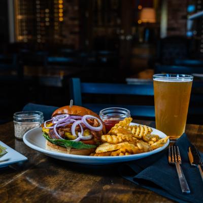The Brewhouse burger with waffle fries and beer on a wooden table.