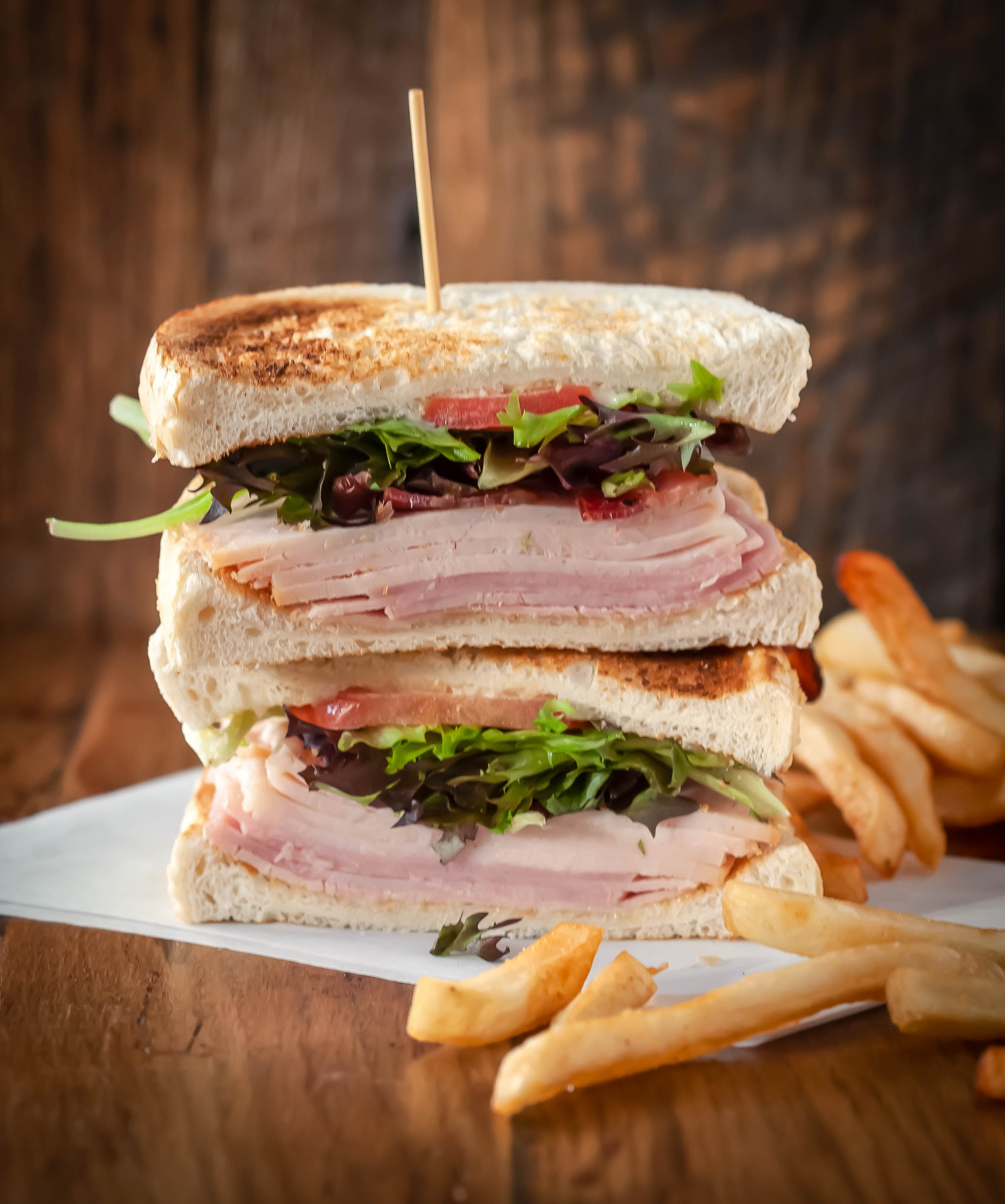 Club sandwich stacked high alongside fries