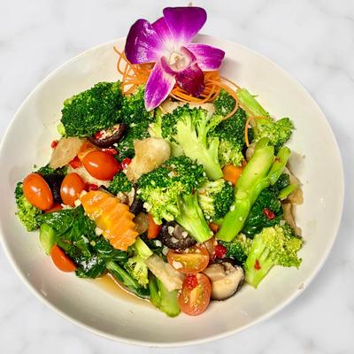 Stir-fried broccoli and mixed vegetables served in a bowl with an orchid.