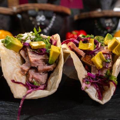 Grilled meat tacos with avocado, cabbage slaw, cilantro, and cheese.