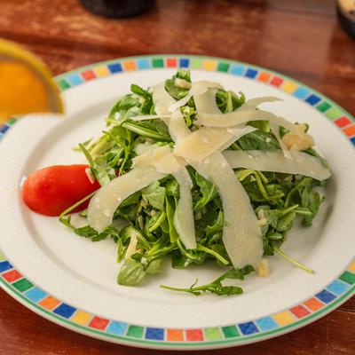 Arugula salad with parmesan on a patterned plate.
