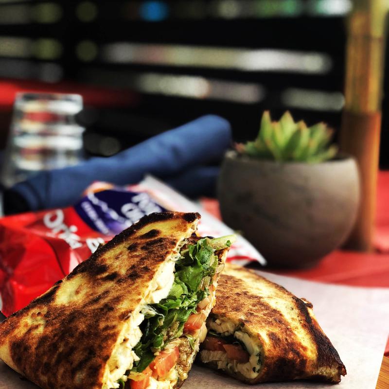 The very best organic chicken sandwich with tomato, field greens and     balsamic vinaigrette, sandwiched in our house made bread (Serranos are      in there unless that scares you).  All that and a bag of chips. photo