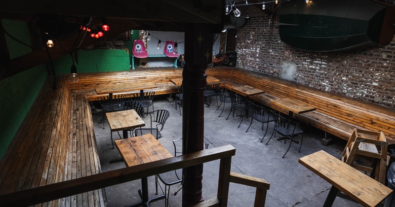 Outdoor seating area with wooden benches, tables, metal chairs, and string lights